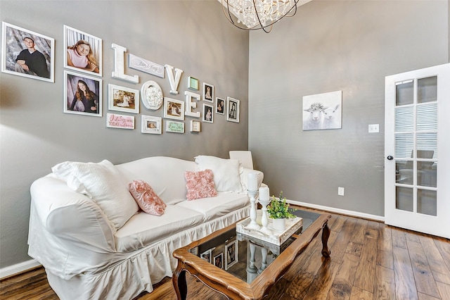 living room with baseboards, an inviting chandelier, and hardwood / wood-style flooring