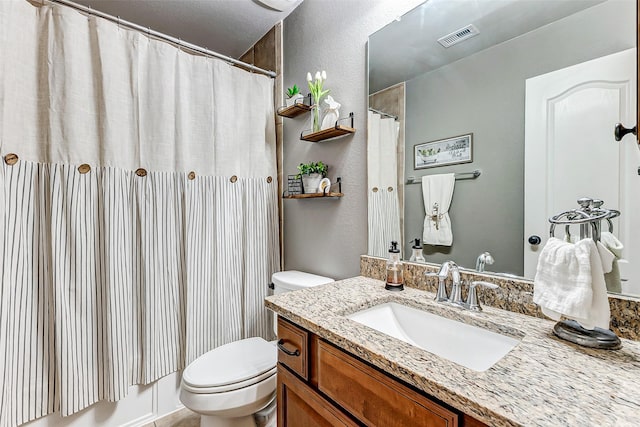 full bath with visible vents, toilet, a shower with shower curtain, a textured wall, and vanity