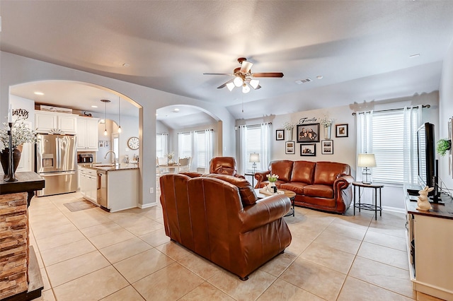 living area featuring visible vents, arched walkways, light tile patterned flooring, and a ceiling fan