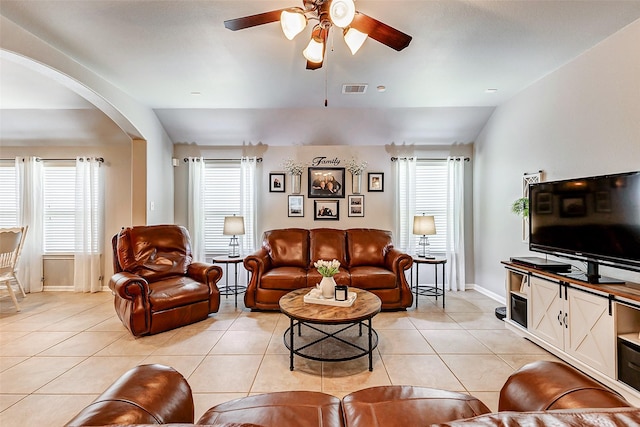 living room featuring visible vents, lofted ceiling, light tile patterned flooring, arched walkways, and ceiling fan