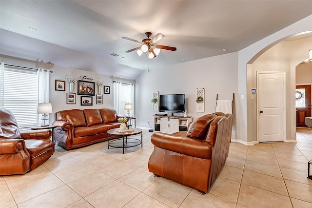 living area with ceiling fan, arched walkways, a healthy amount of sunlight, and light tile patterned flooring