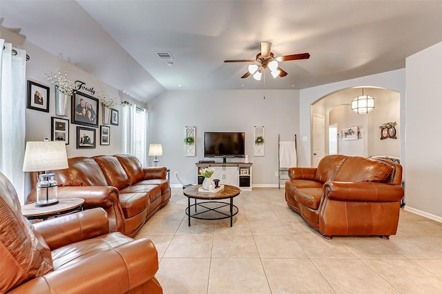 living area featuring light tile patterned floors, baseboards, visible vents, arched walkways, and ceiling fan