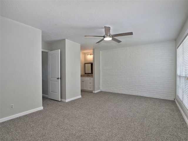 spare room featuring light colored carpet, baseboards, a ceiling fan, and brick wall