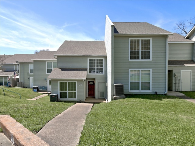 view of front of house with central air condition unit, roof with shingles, and a front yard