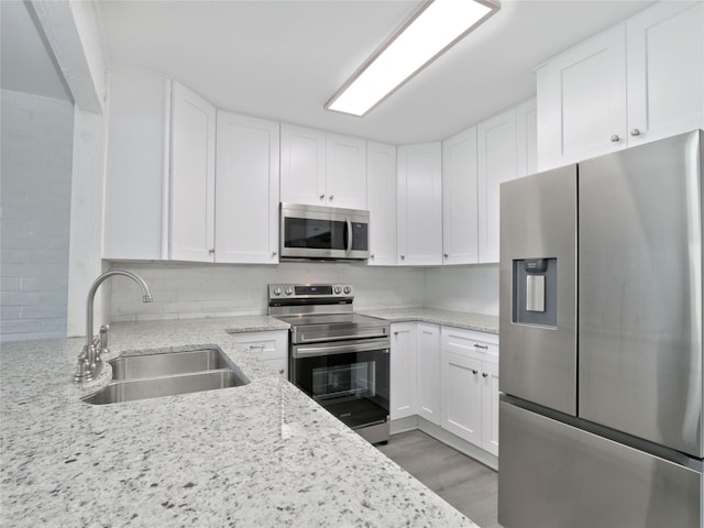 kitchen featuring a sink, stainless steel appliances, light stone countertops, and white cabinets