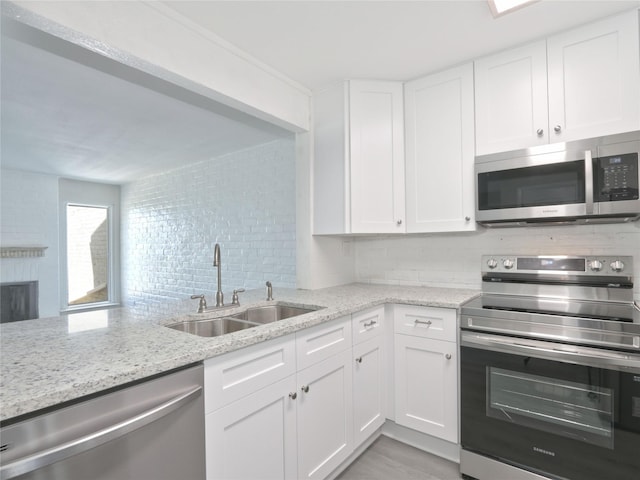 kitchen featuring light stone counters, a sink, decorative backsplash, white cabinets, and appliances with stainless steel finishes