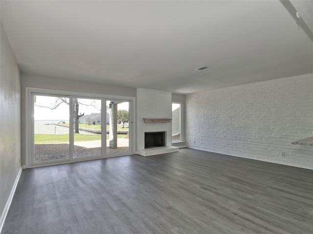 unfurnished living room with baseboards, dark wood finished floors, a fireplace, and visible vents