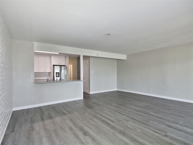 unfurnished living room with baseboards and dark wood-style floors