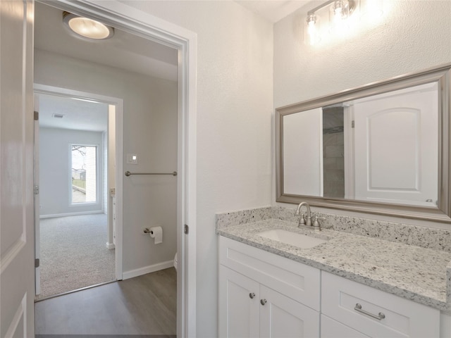 bathroom with toilet, baseboards, wood finished floors, and vanity