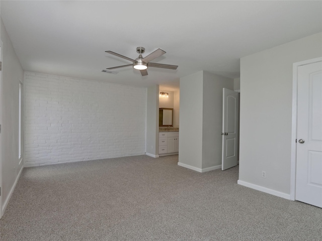 interior space featuring baseboards, visible vents, brick wall, and ceiling fan