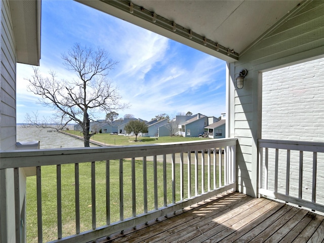 wooden terrace with a water view, a residential view, and a lawn