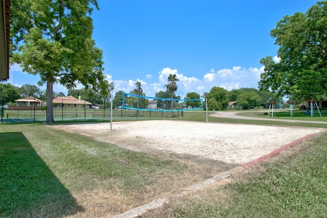 surrounding community with a lawn, volleyball court, and fence