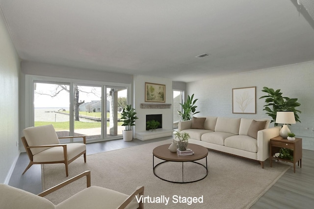 living room with a fireplace with raised hearth, visible vents, and wood finished floors