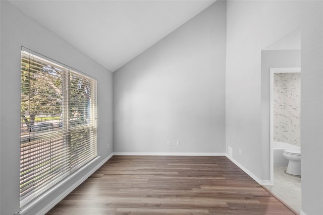 empty room with baseboards, lofted ceiling, and wood finished floors