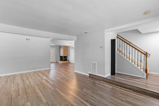 unfurnished living room featuring stairs, wood finished floors, and visible vents