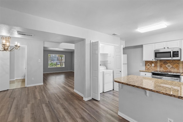 kitchen with visible vents, stainless steel appliances, decorative backsplash, white cabinets, and independent washer and dryer