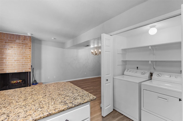 laundry area with laundry area, a fireplace, separate washer and dryer, light wood-style floors, and a notable chandelier