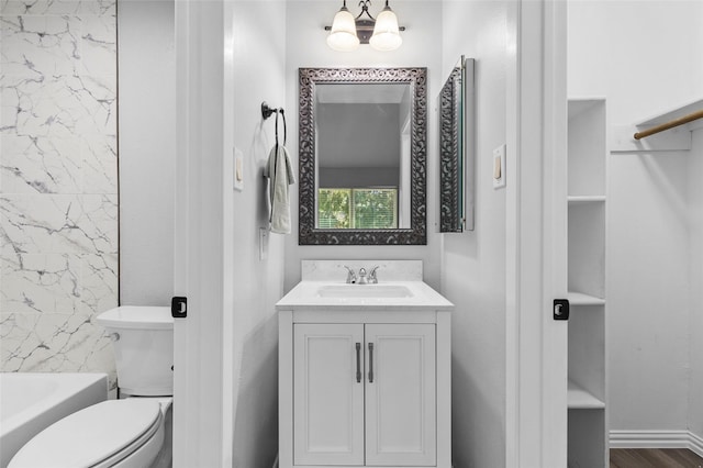 full bathroom with a notable chandelier, toilet, a tub to relax in, wood finished floors, and vanity