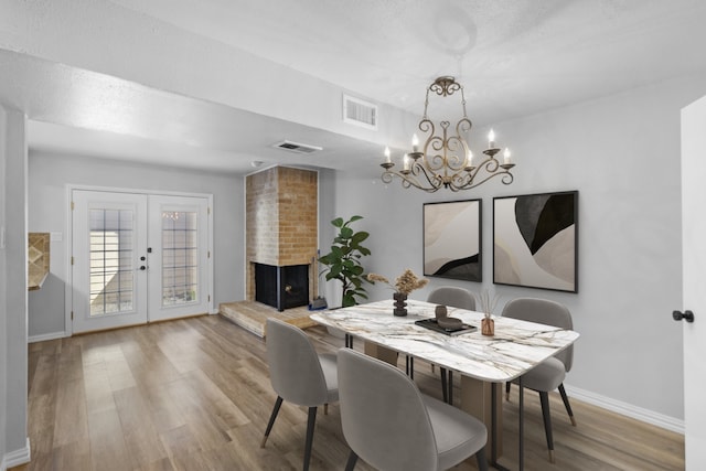 dining room with a fireplace, wood finished floors, visible vents, and french doors