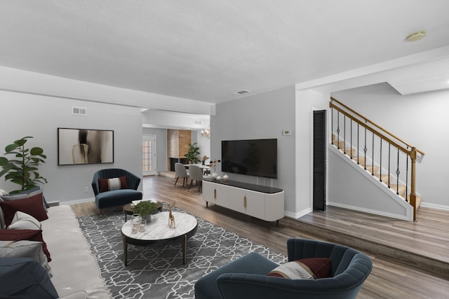 living room with visible vents, stairs, baseboards, and wood finished floors