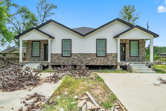 view of front of property with stone siding, stucco siding, a shingled roof, and covered porch