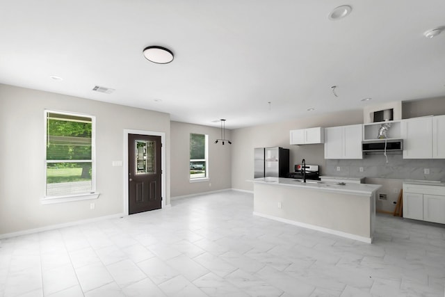 kitchen featuring visible vents, white cabinetry, freestanding refrigerator, and decorative backsplash