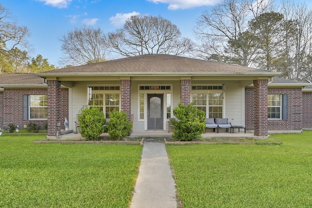 view of front of property featuring a front yard, brick siding, and roof with shingles