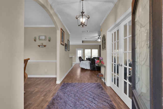 foyer entrance with baseboards, wood finished floors, arched walkways, and ornamental molding