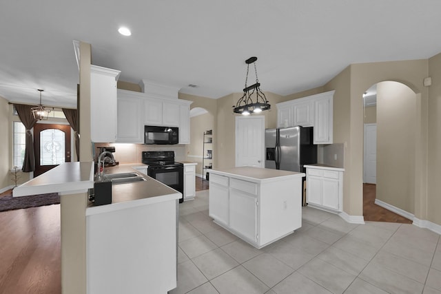 kitchen with black appliances, a sink, a kitchen island, arched walkways, and a peninsula