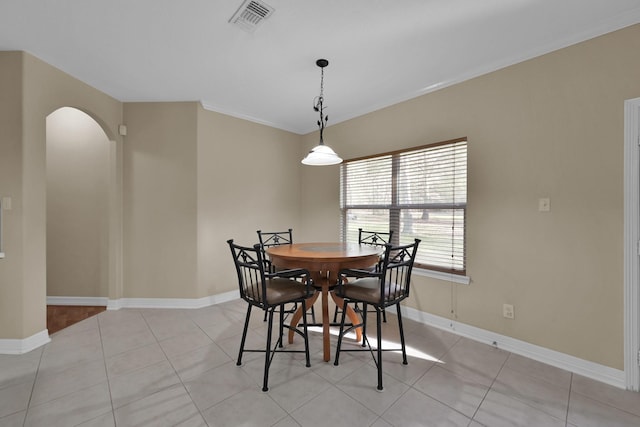 dining room with light tile patterned floors, visible vents, baseboards, arched walkways, and ornamental molding