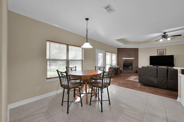 dining room featuring visible vents, baseboards, a tray ceiling, light tile patterned floors, and a fireplace