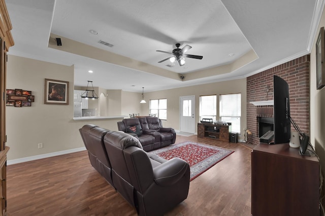 living room with a tray ceiling, baseboards, visible vents, and dark wood-type flooring