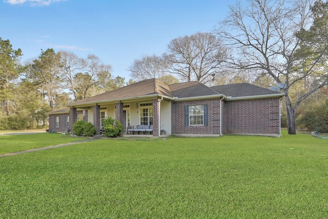 ranch-style house with a front yard, a porch, brick siding, and roof with shingles