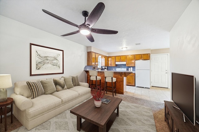 living room featuring light tile patterned floors, light colored carpet, and a ceiling fan