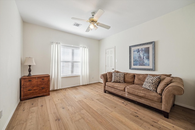 living area with visible vents, light wood-style flooring, baseboards, and ceiling fan