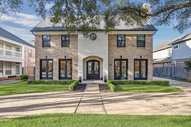 view of front facade with french doors, brick siding, roof with shingles, and fence