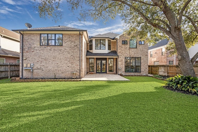 back of property with brick siding, a lawn, french doors, and a fenced backyard