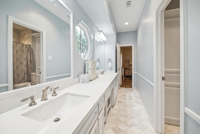 ensuite bathroom with a sink, visible vents, toilet, and double vanity