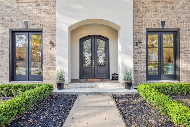 property entrance featuring french doors and brick siding