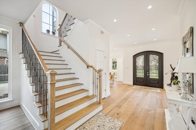 foyer with crown molding, recessed lighting, french doors, wood finished floors, and arched walkways