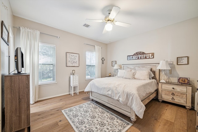 bedroom featuring baseboards, visible vents, light wood finished floors, and ceiling fan