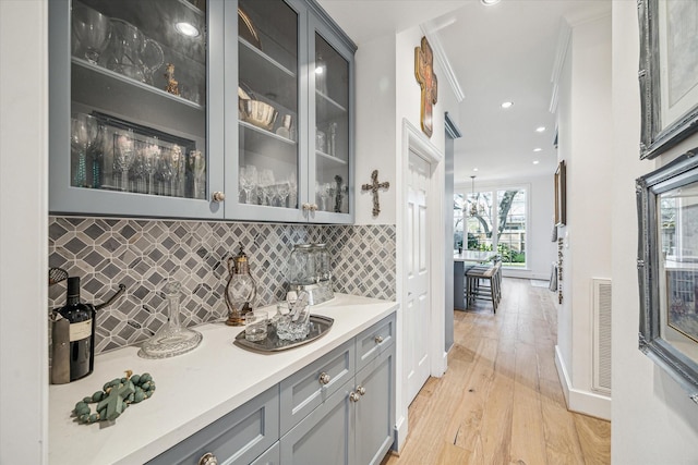 bar featuring visible vents, crown molding, decorative backsplash, recessed lighting, and light wood-style floors