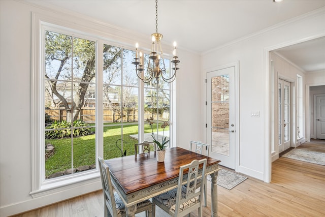 dining space featuring a chandelier, baseboards, light wood-style flooring, and crown molding