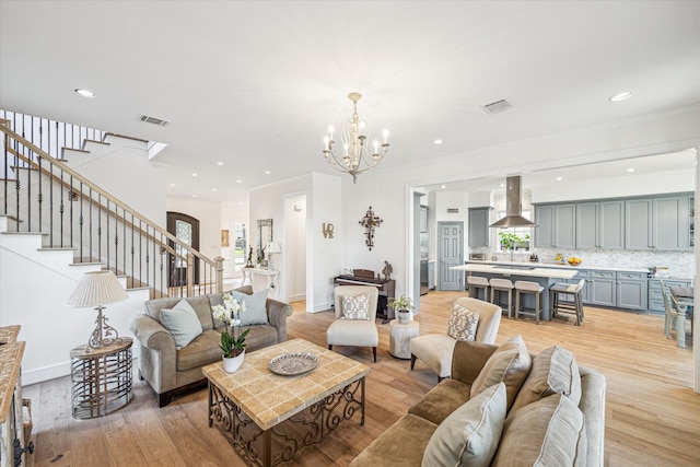 living area featuring stairs, light wood-style flooring, visible vents, and ornamental molding