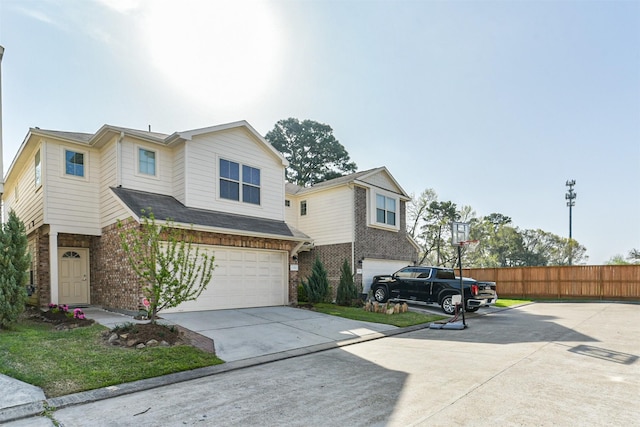 view of front of house with an attached garage, fence, brick siding, and driveway