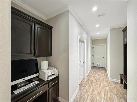 hallway featuring visible vents, baseboards, light wood-style floors, and ornamental molding