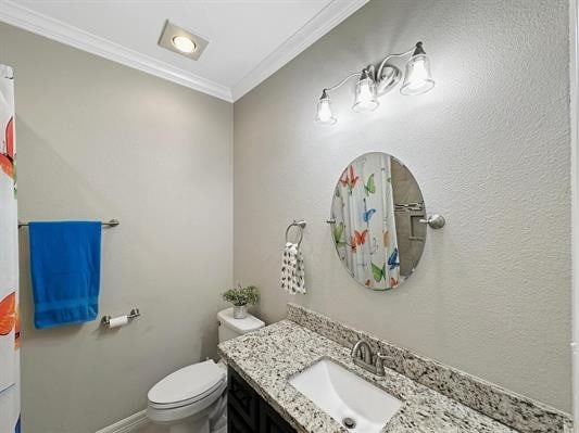 bathroom with vanity, crown molding, toilet, and baseboards