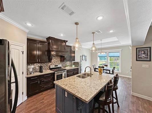 kitchen with visible vents, a breakfast bar, freestanding refrigerator, stainless steel gas stove, and a sink