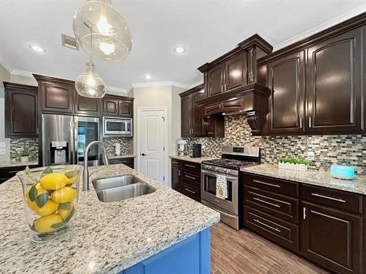 kitchen featuring crown molding, dark brown cabinetry, hanging light fixtures, stainless steel appliances, and a sink