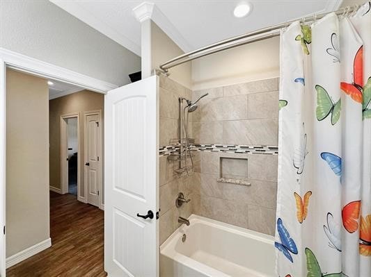 full bathroom featuring ornamental molding, shower / tub combo, baseboards, and wood finished floors